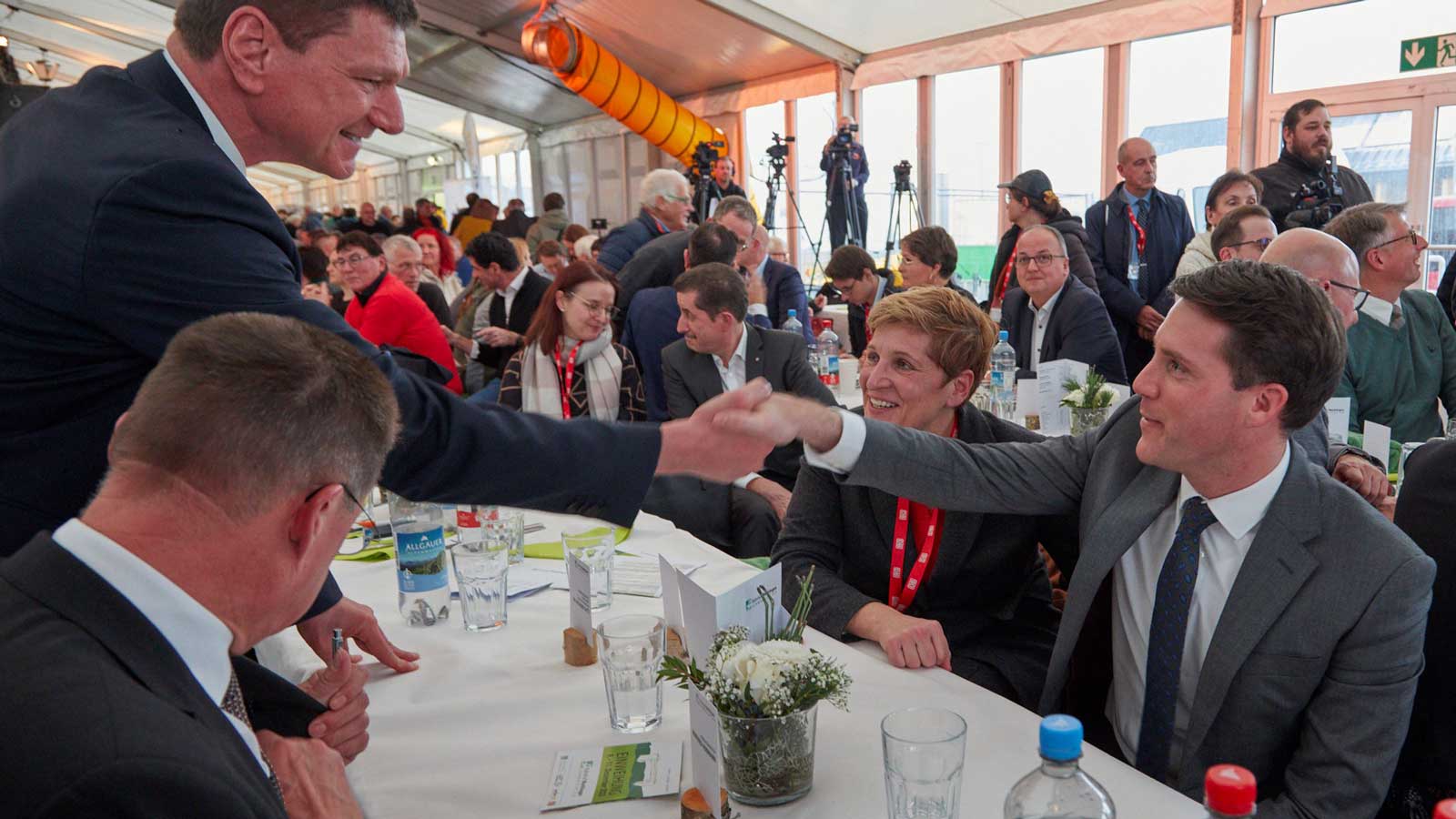 Bürgermeister Klaus Kaufmann und Fraktionsvorsitzender der CDU Manuel Hagel schütteln sich während der Einweihungsfeier am Tisch die Hand