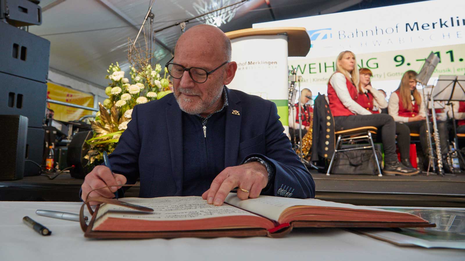 Verkehrsminister Winfried Hermann schreibt während der Einweihungsfeier in ein Buch