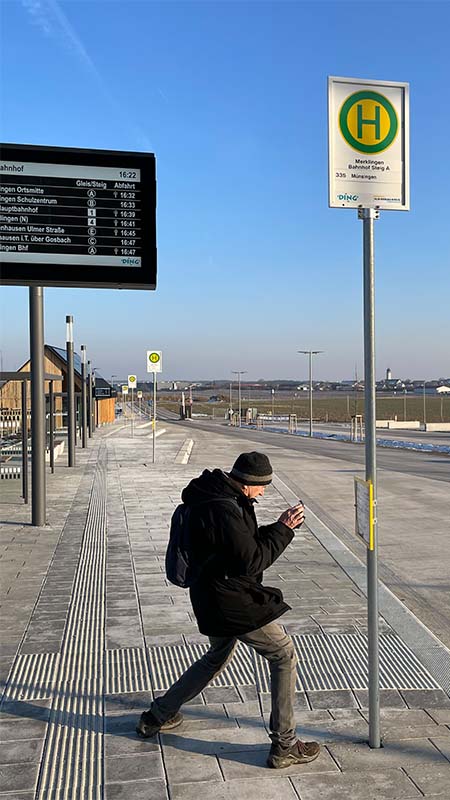 Mann macht ein Foto von dem Buslinienfahrplan